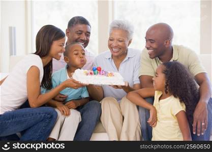 Family in living room smiling with young boy blowing out candles on cake
