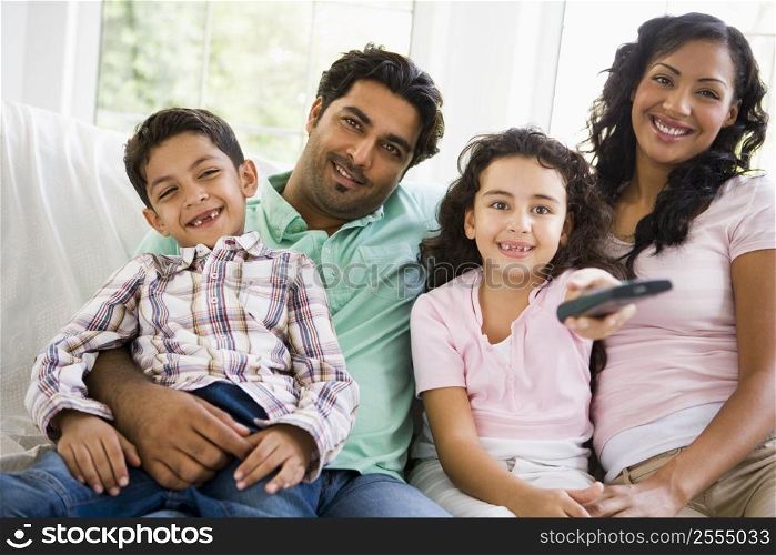 Family in living room with remote control smiling (high key/selective focus)
