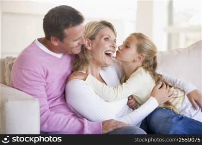 Family in living room with young girl kissing woman