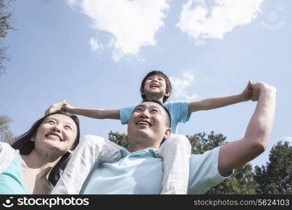 Family in park with son on father&rsquo;s shoulders.