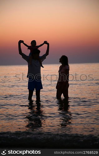 Family in sea alongshore on sunset