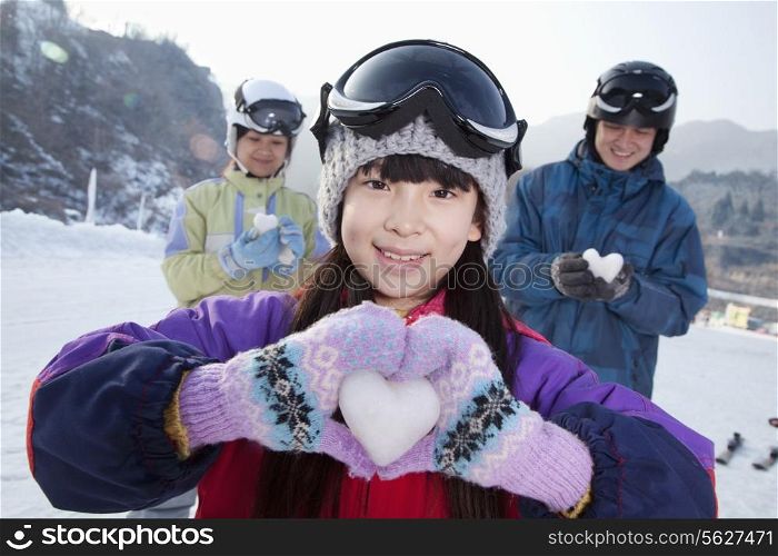 Family in Ski Resort, Daughter Showing Snow Heart