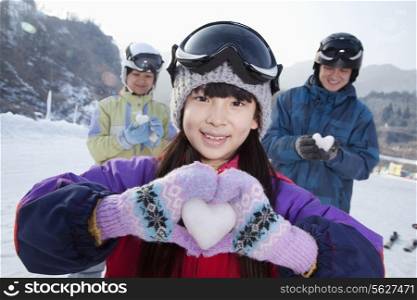 Family in Ski Resort, Daughter Showing Snow Heart