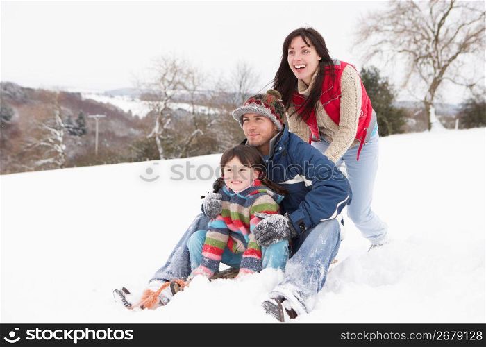 Family In Snow Riding On Sledge