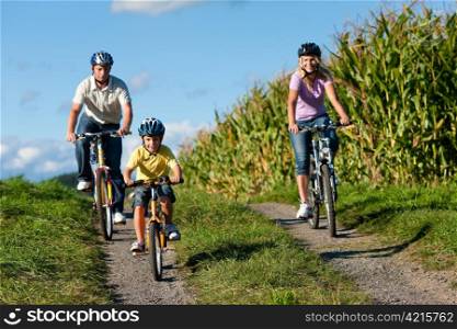 Family is cycling in summer - here mother, father and son