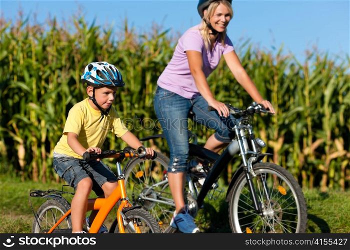 Family is cycling on their bicycles in summer - here mother with son