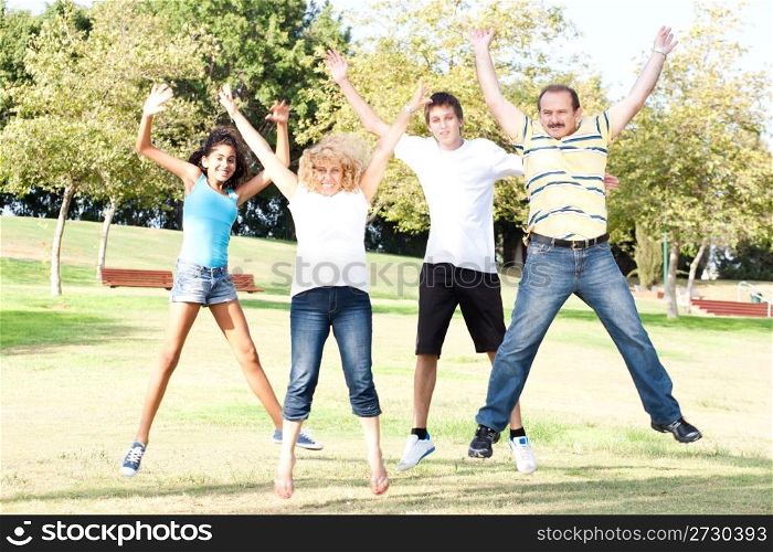 Family jumping high in the air on a green meadow at a late summer afternoon...
