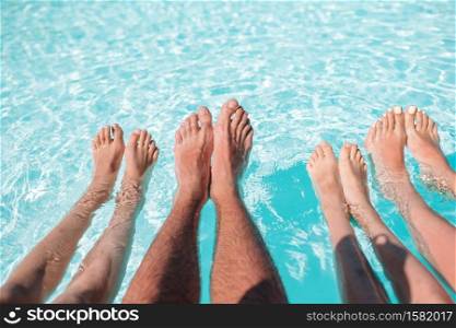 Family legs underwater in the swimming pool. Close up of four people&rsquo;s legs by pool side