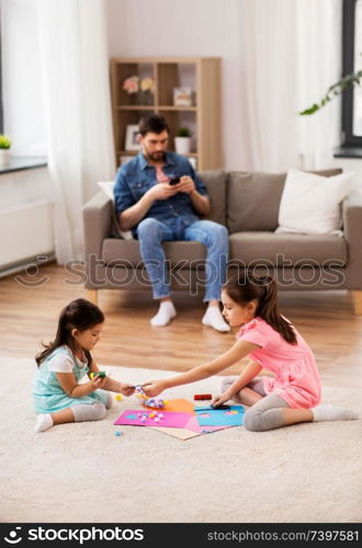family, leisure and childhood concept - happy sisters doing arts and crafts at home. happy sisters doing arts and crafts at home