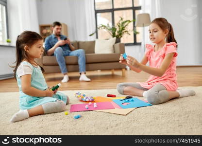 family, leisure and childhood concept - happy sisters doing arts and crafts at home. happy sisters doing arts and crafts at home