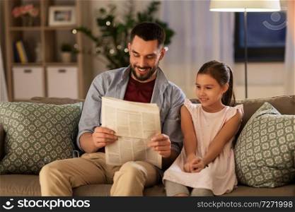family, leisure and people concept - happy father and daughter reading newspaper at home. father reading newspaper to daughter at home