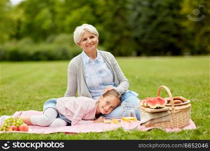 family, leisure and people concept - happy grandmother and granddaughter having picnic at summer park. grandmother and granddaughter at picnic in park
