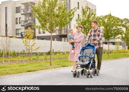 family, leisure and people concept - happy mother and father with little son and stroller walking along city street. family with baby and stroller walking along city