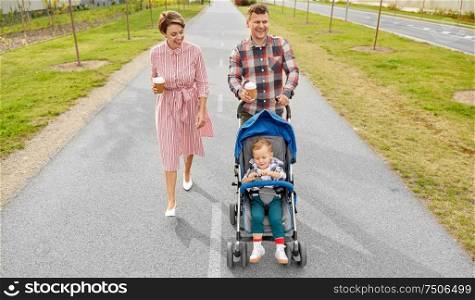 family, leisure and people concept - happy mother and father with little son in stroller and takeaway coffee walking along city street. family with baby in stroller and coffee in city