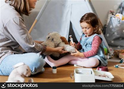 family, leisure and people concept - happy mother and little baby daughter playing doctor at home. mother and daughter playing doctor at home