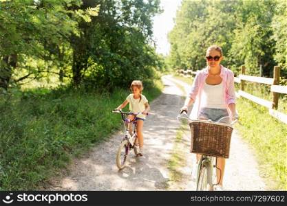 family, leisure and people concept - happy mother and little daughter riding bikes in summer park. mother and daughter riding bikes in summer park