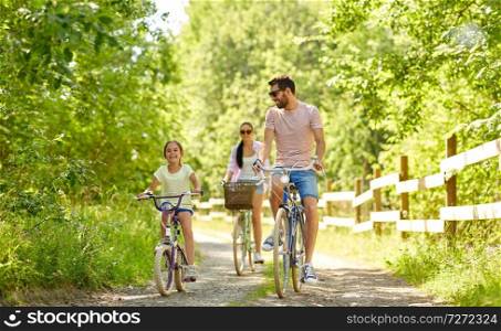 family, leisure and people concept - happy mother, father and little daughter riding bicycles in summer park. happy family riding bicycles in summer park