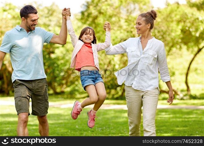 family, leisure and people concept - happy mother, father and little daughter walking in summer park and having fun. happy family walking in summer park