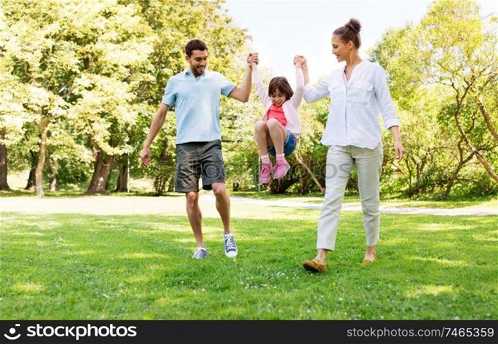 family, leisure and people concept - happy mother, father and little daughter walking in summer park and having fun. happy family walking in summer park
