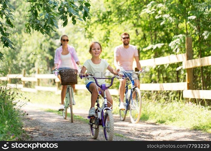 family, leisure and people concept - happy mother, father and little daughter riding bicycles in summer park. happy family riding bicycles in summer park