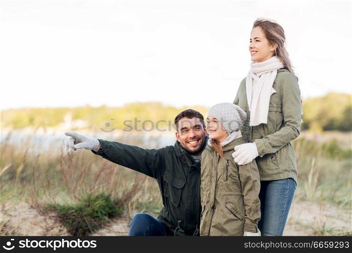 family, leisure and people concept - happy mother, father and little daughter on autumn beach. happy family on autumn beach