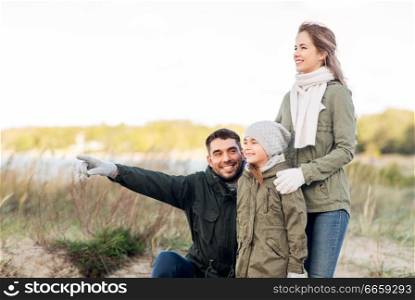 family, leisure and people concept - happy mother, father and little daughter on autumn beach. happy family on autumn beach