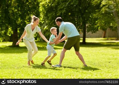 family, leisure and people concept - happy mother, father and little son running and playing catch game at summer park. happy family playing at summer park