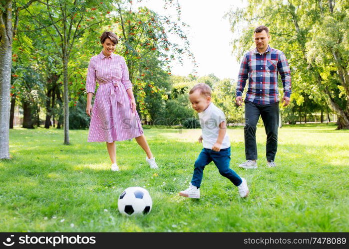 family, leisure and people concept - happy mother, father and little son with ball playing soccer at summer park. happy family playing soccer at summer park