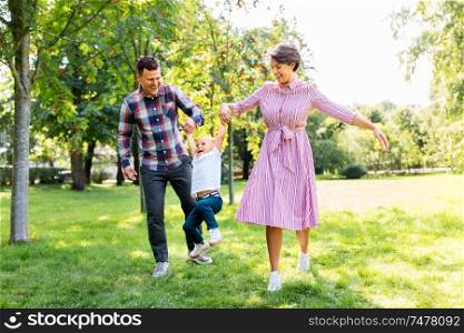 family, leisure and people concept - happy mother, father and little son having fun at summer park. happy family having fun at summer park