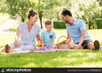 family, leisure and people concept - happy mother, father and little son having picnic at summer park. happy family having picnic at summer park