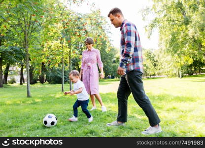 family, leisure and people concept - happy mother, father and little son with ball playing soccer at summer park. happy family playing soccer at summer park