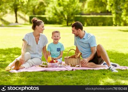 family, leisure and people concept - happy mother, father and little son having picnic at summer park. happy family having picnic at summer park