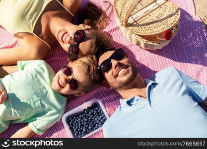 family, leisure and people concept - happy mother, father and little son having picnic on summer beach. happy family having picnic on summer beach