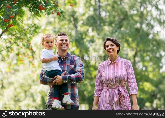 family, leisure and people concept - happy mother, father and little son at summer park. happy family at summer park
