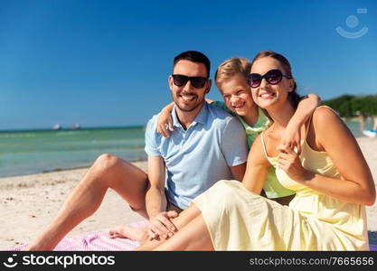 family, leisure and people concept - happy mother, father and little son hugging on summer beach. family hugging on summer beach