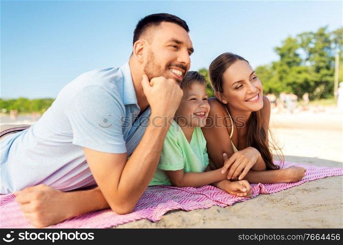family, leisure and people concept - happy mother, father and son lying on summer beach. family lying on summer beach