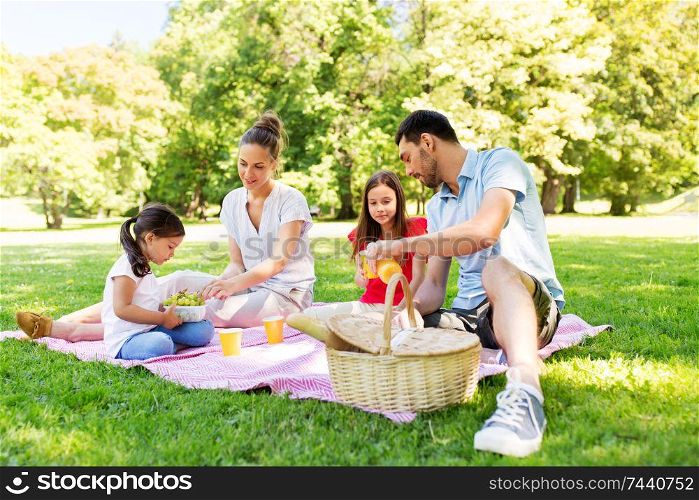 family, leisure and people concept - happy mother, father and two daughters having picnic at summer park. happy family having picnic at summer park