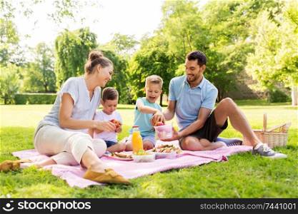 family, leisure and people concept - happy mother, father and two little sons having picnic at summer park. happy family having picnic at summer park