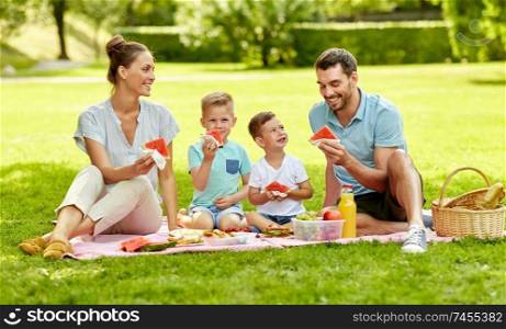 family, leisure and people concept - happy mother, father and two little sons having picnic and eating watermelon at summer park. happy family having picnic at summer park