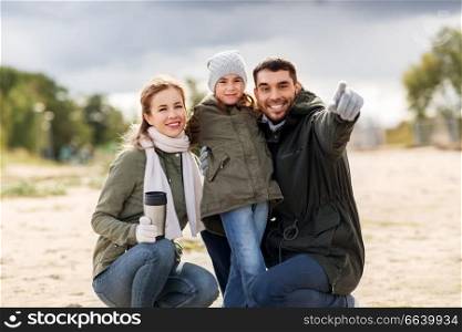 family, leisure and people concept - happy mother with tumbler, father and little daughter outdoors in autumn. happy family outdoors in autumn