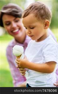 family, leisure and people concept - little boy eating ice cream with mother in summer. little boy eating ice cream with mother in summer