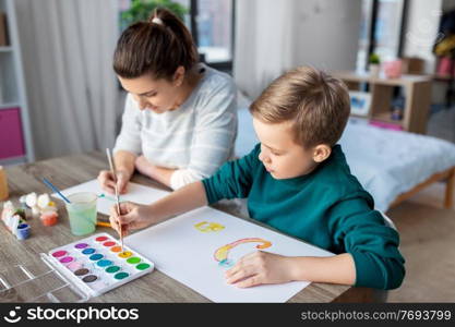 family, leisure and people concept - mother and little son with colors and paper drawing at home. mother and son with colors drawing at home