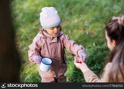 family, leisure and people concept - mother with baby daughter picking berries in park. mother with baby daughter picking berries in park