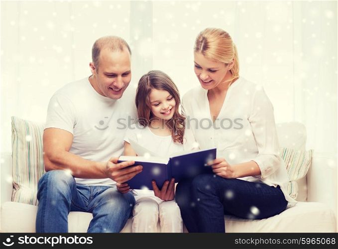 family, leisure, education and people - smiling mother, father and little girl reading book over snowflakes background