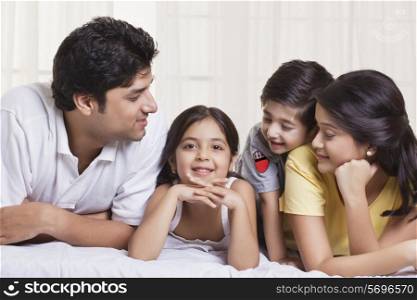 Family looking at little girl while lying in bed