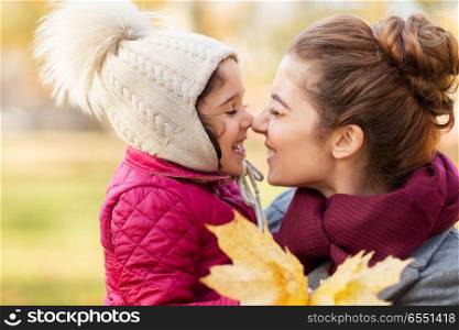 family, love and people concept - happy mother and little daughter with autumn maple leaves rubbing noses. mother and little daughter with autumn leaves. mother and little daughter with autumn leaves