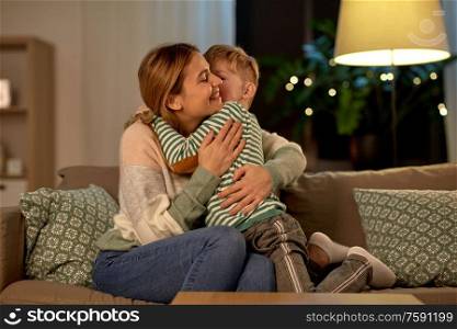 family, love and people concept - happy smiling mother and son hugging at home in evening. happy smiling mother and son hugging at home