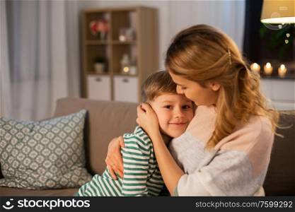 family, love and people concept - happy smiling mother and son hugging at home in evening. happy smiling mother and son hugging at home