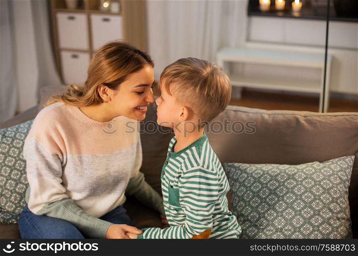 family, love and people concept - happy smiling mother and son touching noses at home in evening. happy mother and son touching noses at home