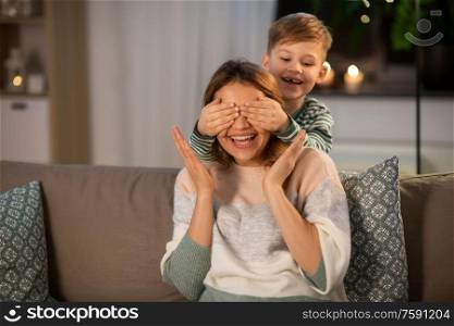family, love and people concept - happy smiling mother playing game with her little son in evening. happy smiling mother playing with her son at home